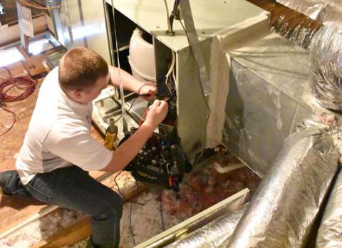  A technician diligently works to repair an HVAC unit